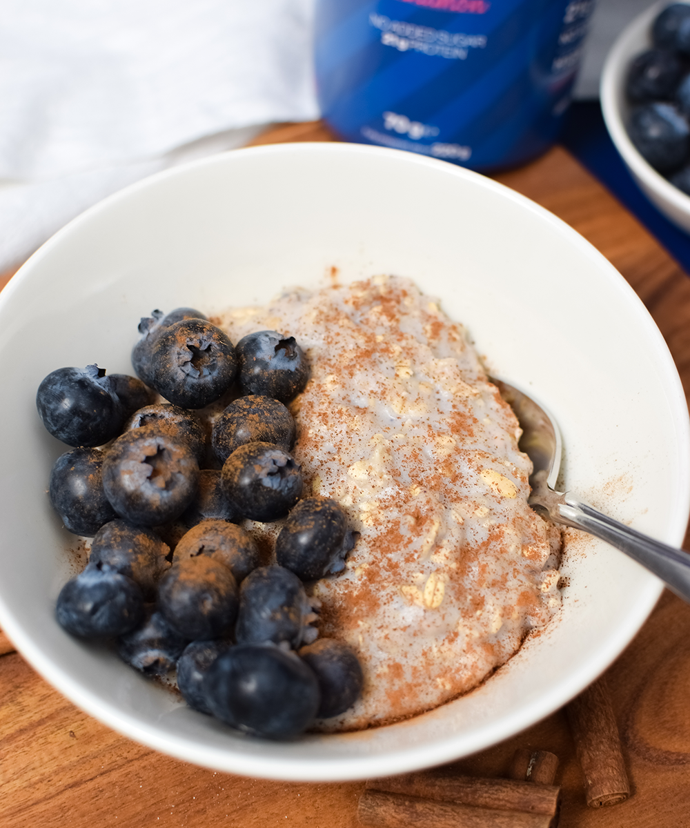 En skål Blueberry Pie Cinnamon Proteingröt toppad med färska blåbär och kanel. En hälsosam och proteinrik frukost eller mellanmål med 21 gram protein och utan tillsatt socker.